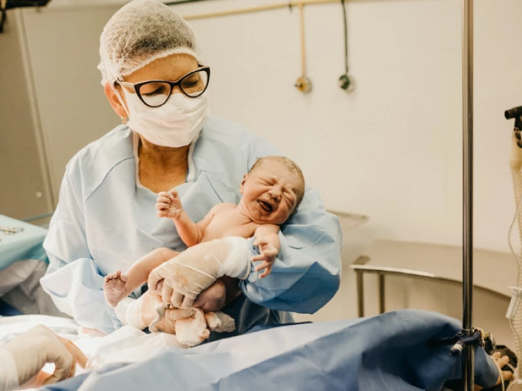 Senior Midwife with newborn after delivery (stock image)
